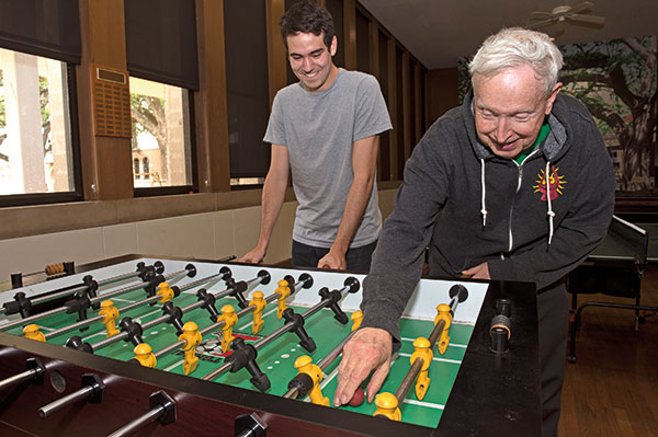 Glibert "Doc C" Cuthbertson plays foosball with a student in the Will Rice game room.